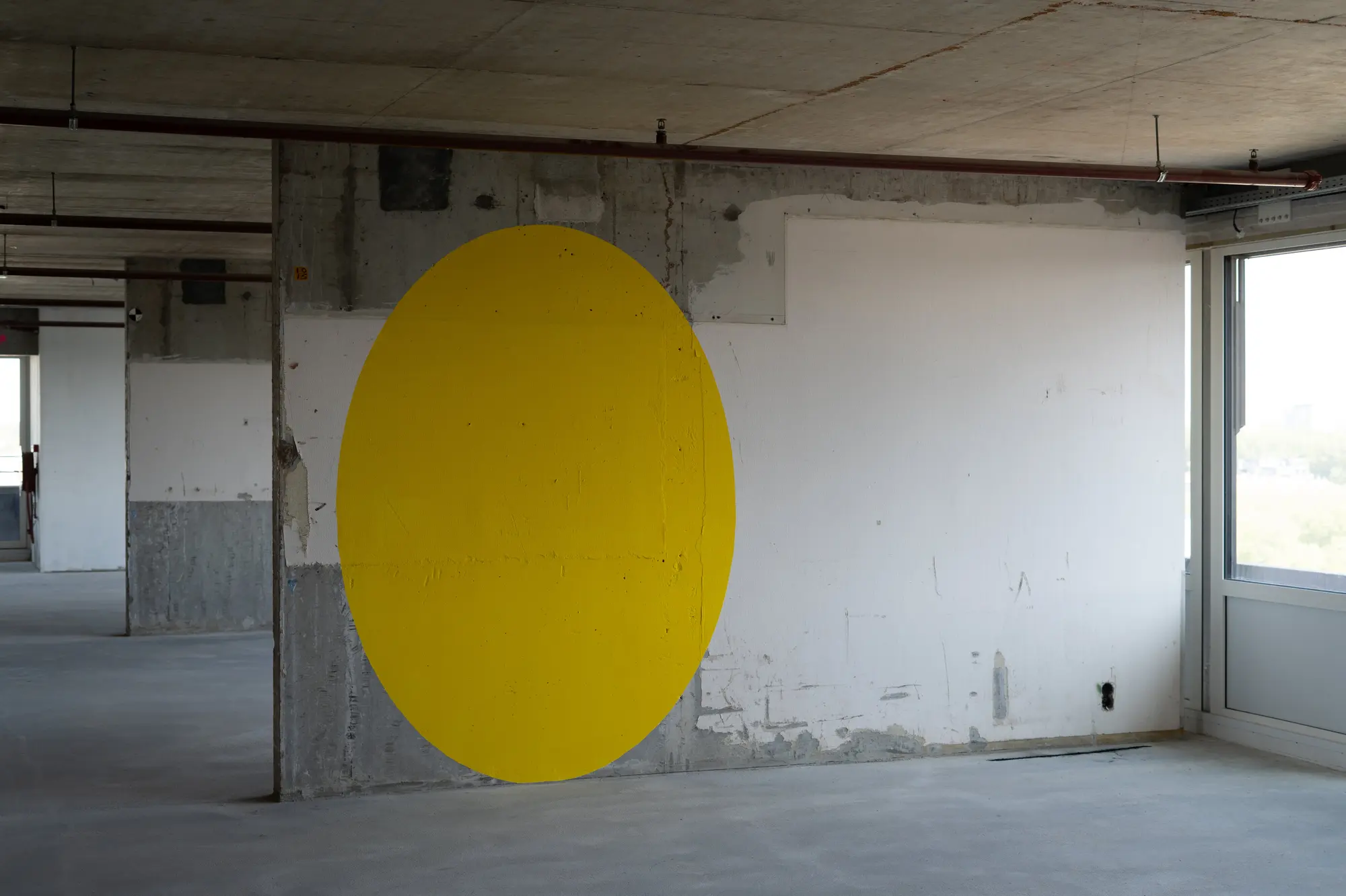 Raw concrete wing at Het Slotervaart with a yellow circle painted on the wall