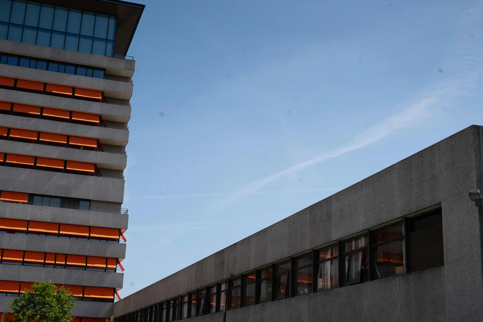 Het Slotervaart in Amsterdam: concrete wings with orange sun blinds under a blue sky